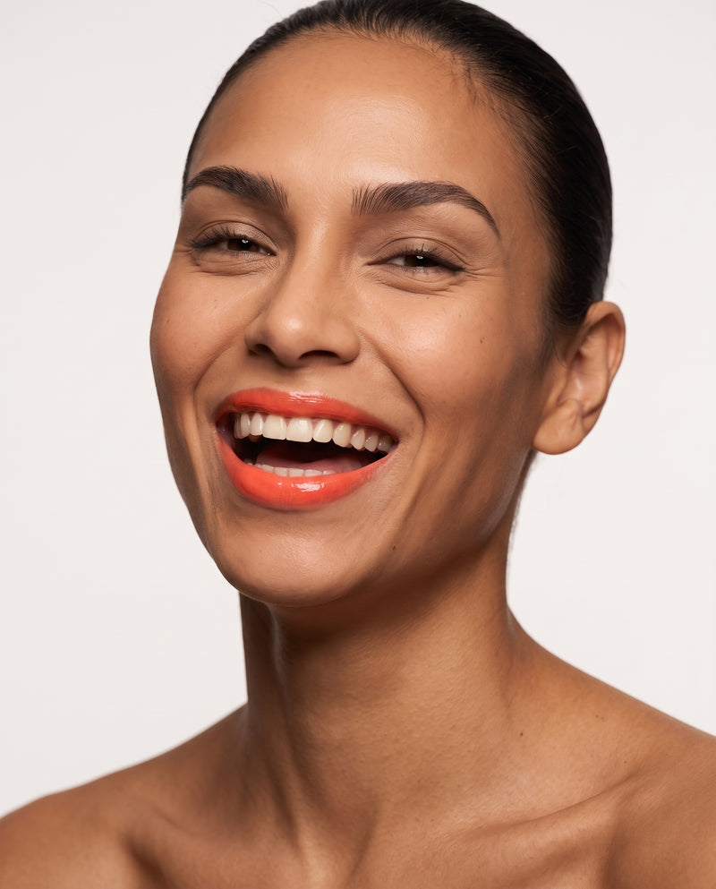 Selena laughing, wearing Coral Honeysuckle tinted lip balm